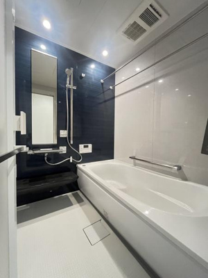 明るい照明が浴室全体を照らし清潔感のある空間を演出しています。ゆとりのあるバスタブは使いやすいデザインです。壁面のアクセントカラーがモダンな印象を与えます。浴室乾燥機もしっかり備え付けられています。