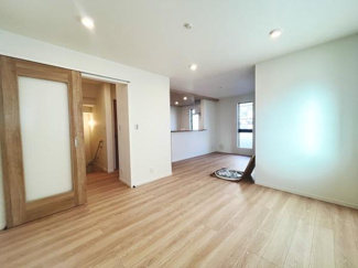 リビングは広々とした空間で明るい木目のフローリングが印象的です。窓からは自然光がしっかり入ります。スライドドアが空間を有効に使えるポイントです。キッチンとのつながりも良く使い勝手が感じられます。