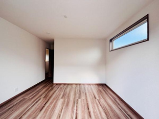 ナチュラルな木目調フローリングが部屋全体を明るく演出します。シンプルな内装で家具の配置がしやすい空間です。高い位置の横長窓から自然光が差し込みます。清潔感のある洋室です。