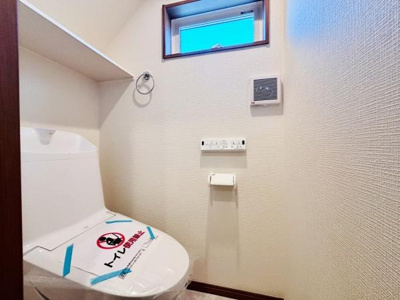 コンパクトなスペースに設計されたトイレです。上部には収納棚が設けられており使い勝手に配慮されています。窓付きで自然光が差し込み明るい雰囲気が感じられます。