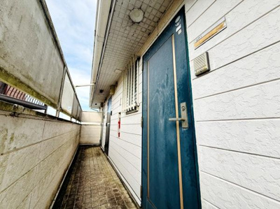 共用廊下がしっかりと確保されており落ち着いた雰囲気が特徴です。玄関扉は鮮やかな色合いで目を引きます。全体的に整理された印象を与え使い勝手のよいスペースです。建物外壁のテクスチャも魅力的です。