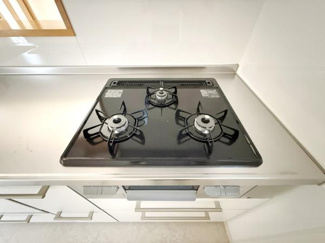 キッチンのガスコンロは3口タイプで複数のお料理を同時に進めやすい設計です。フラットな天板が清掃をサポートします。引き出し収納も備わっており調理道具の整理に便利です。