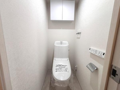 清潔感のある空間が広がるトイレです。収納棚が設置されており小物の整理にも便利です。操作しやすいリモコンが備わっています。シンプルなデザインでお手入れも簡単です。