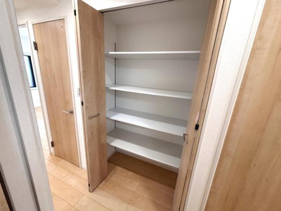 扉付きの収納スペースはホコリを防ぐことができてすっきりとした印象です。棚板が複数あるため物を分けて整理しやすい造りです。廊下の一角に設置されているため使い勝手も便利です。