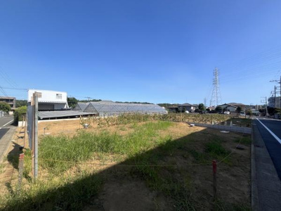 開放感のある現地土地写真です。周囲は住宅や畑が広がり広々とした空間が特徴です。道路に面しているため車の出入りもスムーズに行えます。整った土地で建築計画が立てやすい環境です。