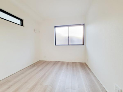 明るい色調のフローリングが印象的な洋室です。大きなクローゼットが設けられており収納スペースも確保されています。上部のスリット窓から自然光が入る設計です。