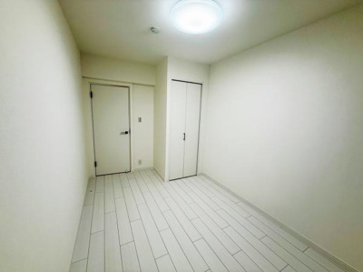 シンプルな内装が特徴の洋室です。白を基調とした落ち着いた空間となっています。クローゼット付きで収納スペースも確保されています。照明が天井に設置され明るさも十分です。使いやすい形状の洋室です。