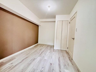 落ち着いた色合いの壁が印象的な洋室です。フローリングのデザインが空間の明るさを引き立てます。収納スペースも確保されており使い勝手の良い一部屋です。シンプルな内装が幅広いインテリアと調和します。