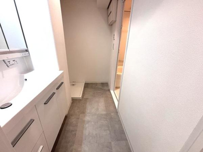 シンプルで清潔感のある洗面所です。収納が豊富な洗面台が魅力です。使いやすい配置で室内も明るく見えます。床はお手入れがしやすい素材になっています。隣接する空間とも行き来しやすい設計です。