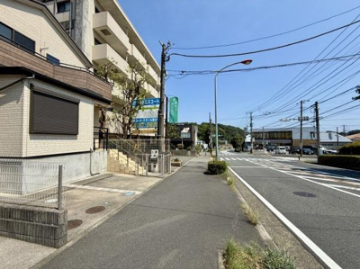 前面道路は広々としており歩道も整備されています。周辺には建物が立ち並び視界が開けた印象です。電柱や街路樹が並び整然とした街並みとなっています。交差点付近に位置し周囲のアクセスも良好です。