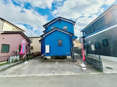 鮮やかな青色の外観が特徴的な一軒家です。敷地内には駐車スペースが確保されています。周囲には落ち着いた住宅が並んでいます。前面道路も広々としています。外観全体がよく手入れされています。