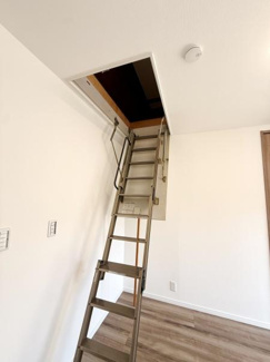 天井収納へのアクセスが可能な折りたたみ式のはしごが設置されています。シンプルなデザインで空間を有効に活用できます。床から天井までスムーズに移動できる仕様です。安全面にも配慮された設計となっています。