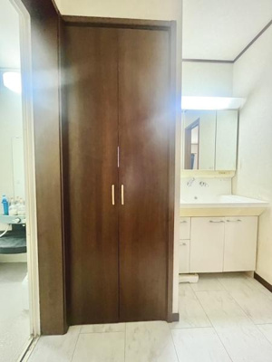 木目調の収納扉が存在感を放つ洗面所です。明るい照明で清潔感を感じられます。収納スペースがしっかり確保されており日用品の整理もしやすい造りです。洗面台もシンプルで使いやすいデザインです。