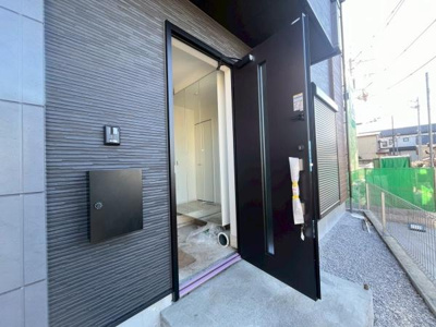 玄関扉はシンプルで洗練されたデザインです。外壁の質感が現代的な雰囲気を演出しています。