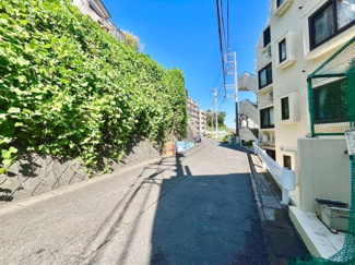 日当たりの良い道路沿いの風景が広がっています。周辺には緑の生垣がしっかりと整備されています。道幅もゆったりとしており歩きやすい環境です。建物の外観も清潔感があります。