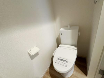 シンプルですっきりとしたデザインのトイレです。壁紙と床の色のコントラストが印象的です。ペーパーホルダーなど必要な設備がしっかり整っています。清潔感のあるスペースとなっています。