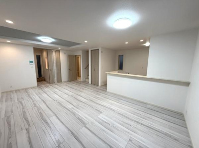 広々とした空間が広がるリビングは開放感を感じられます。白を基調とした内装が明るさを際立たせています。床材の質感が高級感を演出しています。ダウンライトとシーリングライトが柔らかい光を提供します。