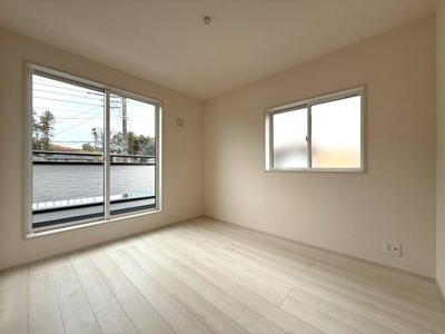 大きな窓があるため日差しがしっかりと入る洋室です。壁や床の色合いが落ち着いており室内がすっきりとした印象です。家具の配置もしやすいシンプルなレイアウトです。