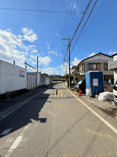前面道路はゆるやかなカーブが特徴的で車通りの様子もしっかりと確認できます。明るい空の下周辺環境も開放的です。整備された舗装道路が続き現地の雰囲気を直接感じられます。
