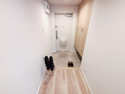 ナチュラルな色合いの玄関が全体的に明るく仕上がっています。収納スペースがしっかり備えられておりすっきりした印象です。靴の収納ラックが配置されスマートな空間利用が特徴的です。