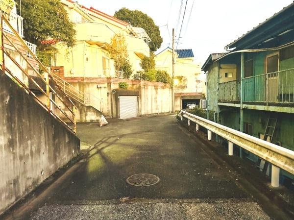 現地前面道路は幅が広く車の出入りもしやすい環境となっています。道路沿いには住宅が建ち並び落ち着いた雰囲気が感じられます。坂道も整備されており歩行にも便利です。
