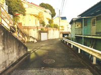 現地前面道路は幅が広く車の出入りもしやすい環境となっています。道路沿いには住宅が建ち並び落ち着いた雰囲気が感じられます。坂道も整備されており歩行にも便利です。