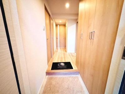 木目調のデザインが温かみのある雰囲気を演出しています。広々とした玄関スペースで開放感があります。収納が充実しておりすっきりと整理しやすい設計です。照明が明るく玄関全体が爽やかに映えます。