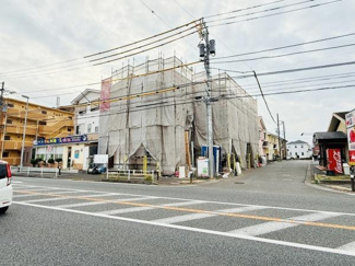 現地は大通りに面しており周辺には店舗や住宅が立ち並んでいます。建物は現在工事中です。交差点に近い立地なので目印になりやすい場所です。道路幅が広く交通アクセスも良好です。