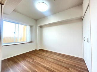 明るい光が差し込む洋室です。落ち着いた色合いのフローリングが空間に調和しています。使い勝手の良い収納スペースも備わっています。窓からの採光が十分に確保されています。清潔感のある室内です。