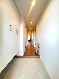 玄関には収納スペースが備わっておりすっきりとした印象です。明るい照明が廊下を照らしており清潔感があります。床面もフラットで安全に配慮されています。奥まで見通しの良い空間です。
