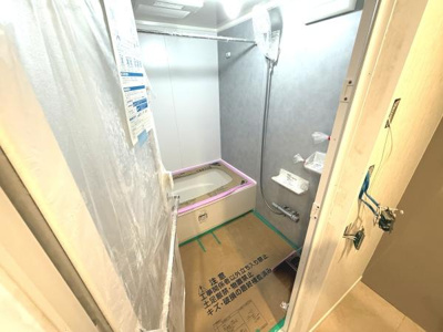 新しい設備が設置されたバスルームです。清潔感のある空間が印象的です。壁や浴槽の色合いも落ち着いています。シンプルなレイアウトが魅力となっています。リフォーム直後の状態が確認できます。