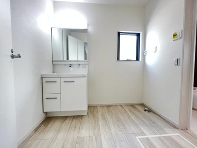 シンプルなデザインの洗面台が設置されておりお手入れも簡単です。小窓からの採光で明るい空間になっています。清潔感ある内装が特徴的です。収納スペースも備わっています。