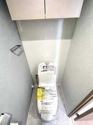 清潔感のある空間が広がるトイレです。壁面や床の色合いが落ち着いており収納も確保されています。使いやすい設計がポイントです。シンプルなデザインが印象的です。