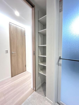 コンパクトなスペースを活かした壁面収納が設置されています。ホワイト基調の内装が明るい印象です。廊下から扉で仕切られておりプライベート空間が確保されています。