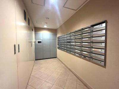 広々とした共用スペースに設置されたメールボックスと宅配ボックスが便利です。整理された印象を与える壁面一面の郵便受けが魅力です。セキュリティにも配慮された設備となっています。清潔感のある内装が特徴です。