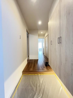 明るい玄関スペースが広がり収納扉も設けられています。木目調の床が空間を引き締めています。天井のダウンライトがすっきりとした印象です。廊下までの動線もスムーズに確保されています。