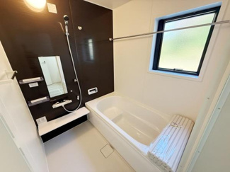 明るい採光の窓があるバスルームです。モダンな壁面デザインが空間を引き締めます。浴室乾燥機付きで機能面も充実しています。シンプルなレイアウトで使い勝手も良好です。