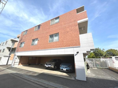 落ち着いた色合いの外観が魅力の建物です。屋根付き駐車スペースがあり雨の日も安心です。周辺は静かな住宅街の雰囲気です。日当たりの良さも感じられます。